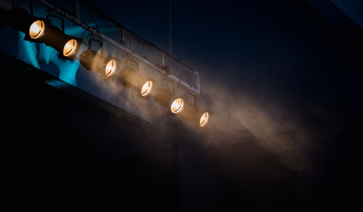 Row of stage spotlights hanging from a ceiling, representing mainstream celebrities crossing into the creator economy