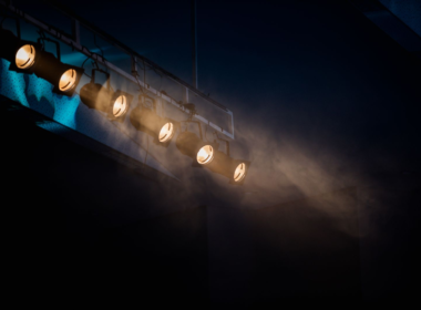 Row of stage spotlights hanging from a ceiling, representing mainstream celebrities crossing into the creator economy