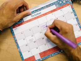 Hands writing on a paper calendar, representing content planning for creators