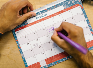 Hands writing on a paper calendar, representing content planning for creators