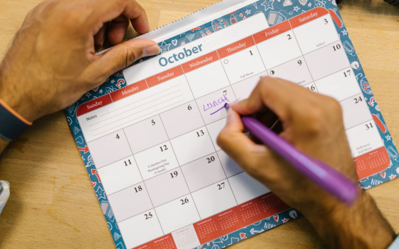 Hands writing on a paper calendar, representing content planning for creators