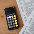 Calculator and tax forms on a wooden desk, representing UK self-assessment tax filing for creators