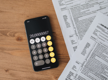 Calculator and tax forms on a wooden desk, representing UK self-assessment tax filing for creators