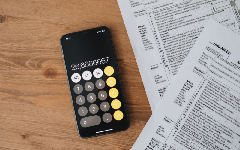 Calculator and tax forms on a wooden desk, representing UK self-assessment tax filing for creators