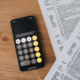 Calculator and tax forms on a wooden desk, representing UK self-assessment tax filing for creators