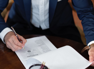 Person signing a legal document, representing UK Online Safety Act age-verification compliance