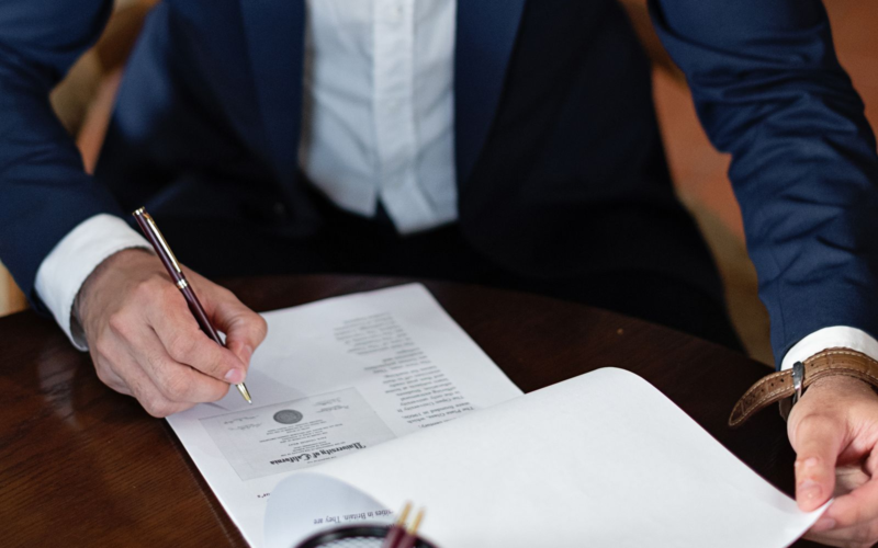 Person signing a legal document, representing UK Online Safety Act age-verification compliance